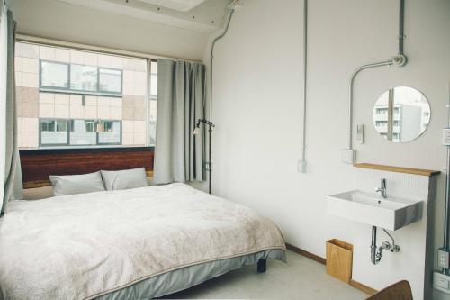 1 dormitorio con cama y lavamanos en CITAN Hostel, en Tokio