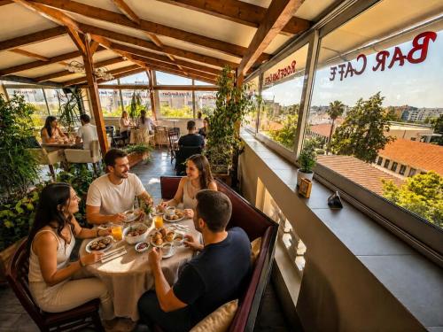 a group of people sitting around a table at a restaurant at Diethnes Hotel in Athens