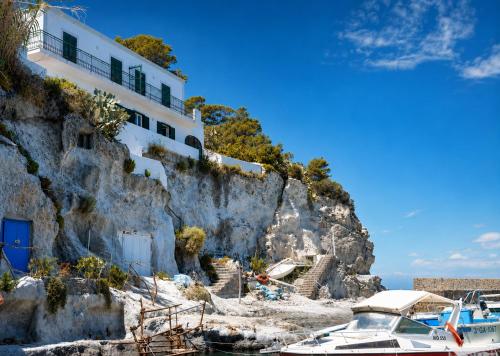 a white house on a cliff next to a boat at Maridea - Donatino a Mare in Ponza