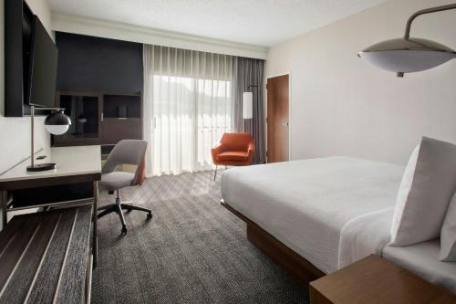 a hotel room with a bed and a desk at Courtyard Syracuse Carrier Circle in East Syracuse