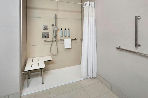 a bathroom with a shower with a bench in it at Courtyard Syracuse Carrier Circle in East Syracuse
