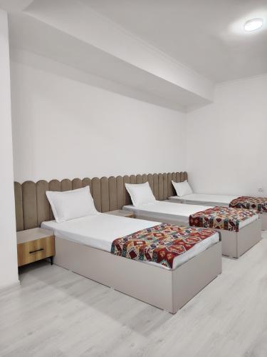 two beds in a room with white walls at Парк апарт-отел in Namangan