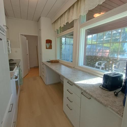 a kitchen with white cabinets and a large window at Villa Aspen in Kokkola