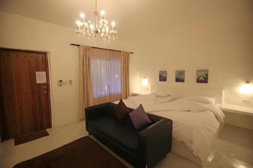 a bedroom with a bed and a chair and a chandelier at Samunthitar Resort in Khao Kho