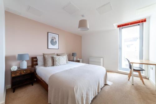 a bedroom with a bed and a desk and a window at Spacious 2 Bed Apartment in Stratford in London