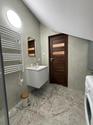a bathroom with a sink and a wooden door at Willa przy Czarnej Bramie in Kłodzko