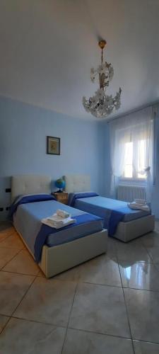 a bedroom with two beds and a chandelier at A casa di Ely in Aulla