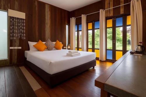 a bedroom with a large white bed with orange pillows at Chababaancham Resort in Amphawa