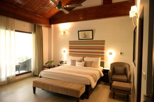 a bedroom with a bed and a chair and a window at Zone Niathu Dimapur By The Park in Dimāpur