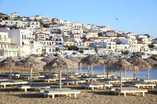 a group of tables and straw umbrellas on a beach at Chryssi Akti, Sure Hotel Collection in Batsi