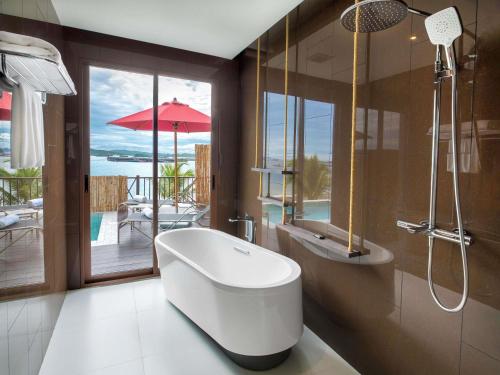 a bathroom with a tub and a view of the ocean at Novotel Koh Si Chang in Ban Phanu Rangsi