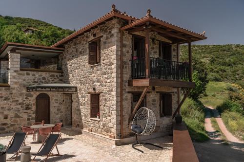 a stone house with a balcony and a table and chairs at La Villa de Madeleine - Stone Villa with outdoor hot tub in Arcadia, Peloponnese in Áyios Ioánnis