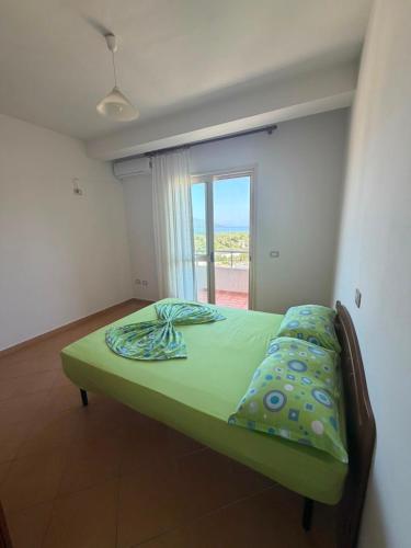 a green bed in a room with a window at A&A Aparthotel in Orikum