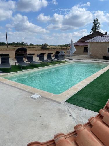 a large swimming pool with lounge chairs and aractor at L’alambic in Guizengeard