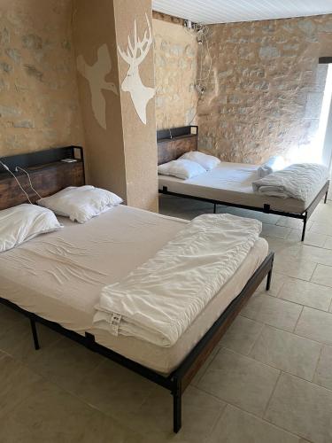 two beds are in a room with a brick wall at L’alambic in Guizengeard