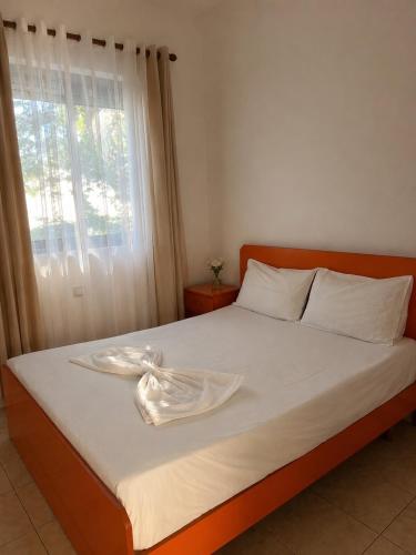 a bed with a white blanket on it with a window at Beachside Apartments Smajlaj in Velipojë