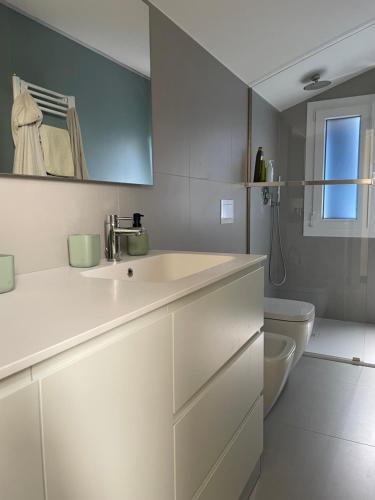 a white bathroom with a sink and a toilet at Casa Ficcanaso in Caorle