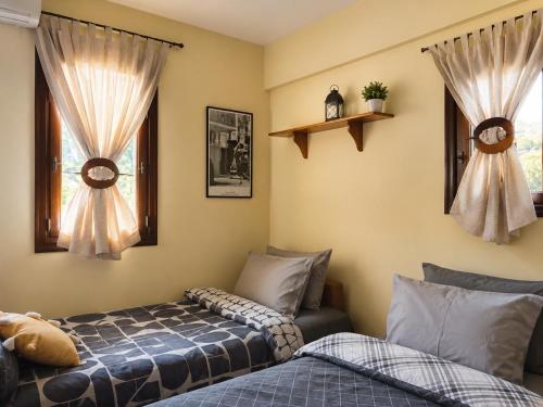 a bedroom with two beds and two windows at Lidori Mani in Akhíllion