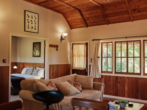 a living room with a couch and a bed at Vineyard Cottages - Kumeu in Waimauku