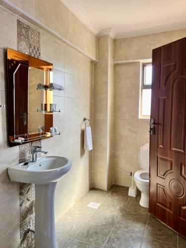 a bathroom with a sink and a toilet and a mirror at Shanvilla Resort Ltd in Murangʼa