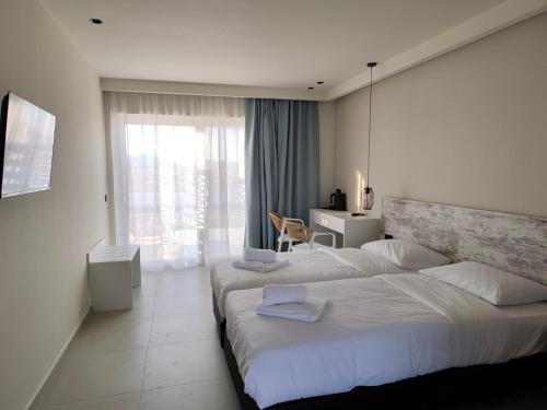 a hotel room with two beds and a window at Evita Flamingo in Kos