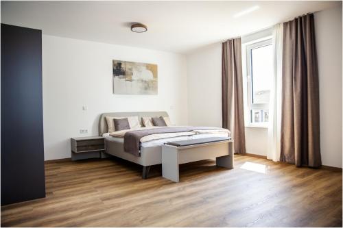 a white bedroom with a bed and a window at Pension Malia in Fronhausen