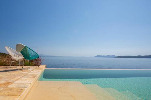 a swimming pool with a view of the water at Villa Arkoudaki Luxurious Escape with Infinity Pool & Sea Access in Évyiros