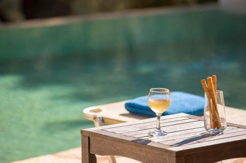 a glass of wine on a wooden table next to a pool at Villa Amoudia - Luxury Villa right on the beach with Private Pool in Sivota