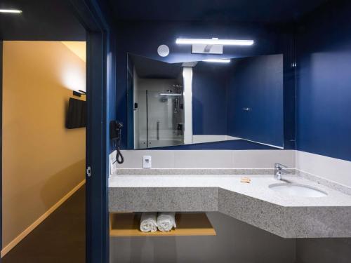 a bathroom with a sink and a large mirror at Ibis Styles Barretos in Barretos
