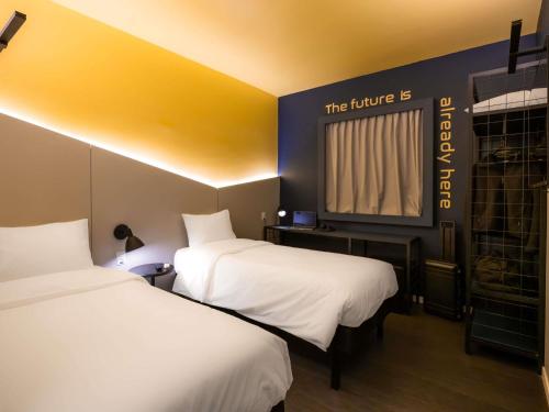 a hotel room with two beds and a window at Ibis Styles Barretos in Barretos