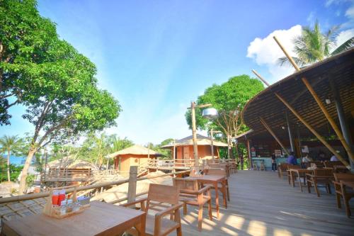 a restaurant with wooden tables and chairs on a deck at The Mud - Eco Hotel in Ban Bang Po