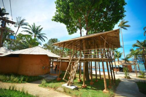 a building with a straw roof next to a house at The Mud - Eco Hotel in Ban Bang Po