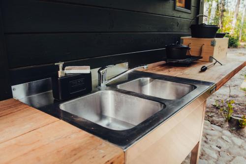 a kitchen counter with a sink and a black wall at Dacza Puchacza Hamaki in Stare Osieczno