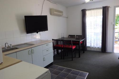 a kitchen with a table and a tv on the wall at Matildas End Holiday Units in Karumba