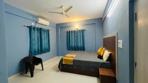 a blue bedroom with a bed and a chair at Fabhotel Aman palace in Mumbai