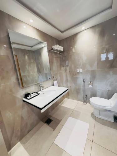 a bathroom with a sink and a toilet and a mirror at Ambassador Hotel in Lahore