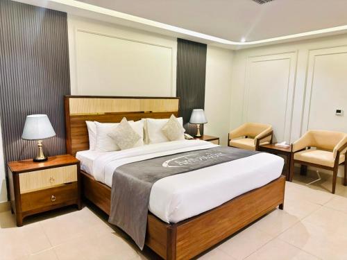 a bedroom with a large bed and a chair at Ambassador Hotel in Lahore