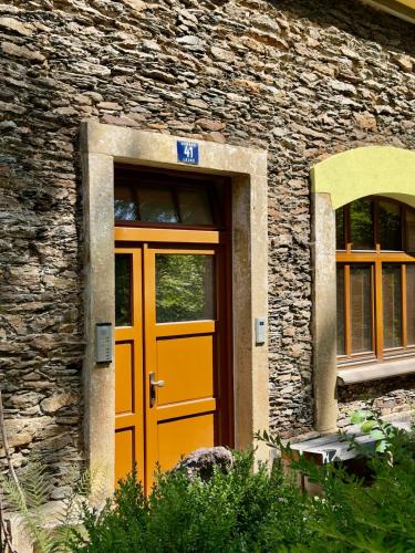 a orange door on a stone building with windows at Apartment Vilém in Janske Lazne