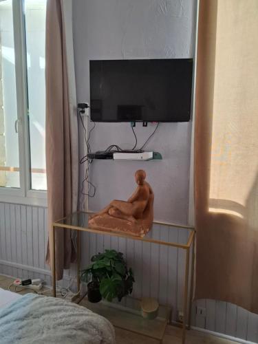 a statue of a man sitting on a shelf under a tv at Studio en toute simplicité plein centre in Libourne