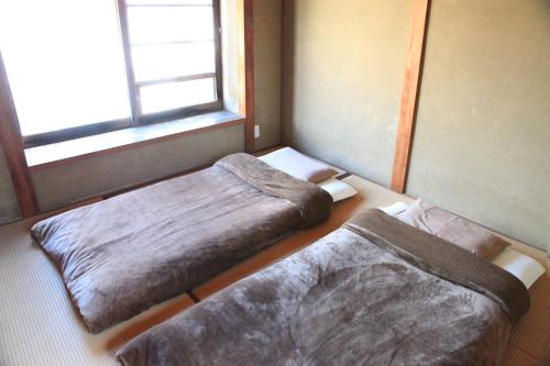 two beds in a room with a window at Okayama Hostel Igusa in Hayashima
