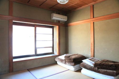 a room with two beds and a window at Okayama Hostel Igusa in Hayashima