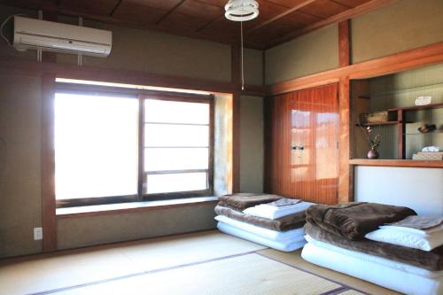 a room with two beds and a window at Okayama Hostel Igusa in Hayashima