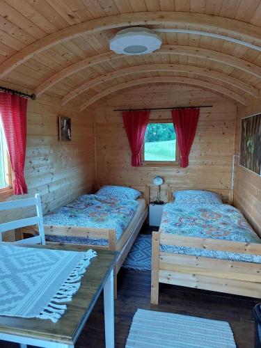 a room with two beds and a table in a cabin at Schäferwagen Weidetraum in Naila