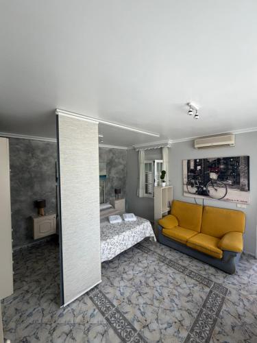 a living room with a yellow couch and a bed at Apartamento turístico ilusiones 5 in Cazalla de la Sierra