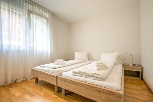 a bedroom with two beds and a window at Moench Apartment - Aare Jungfrau AG in Wilderswil