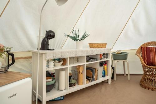 a shelf in a tent with dishes and plants at Tipi Jurte Zelt in der Seenplatte in Carpin