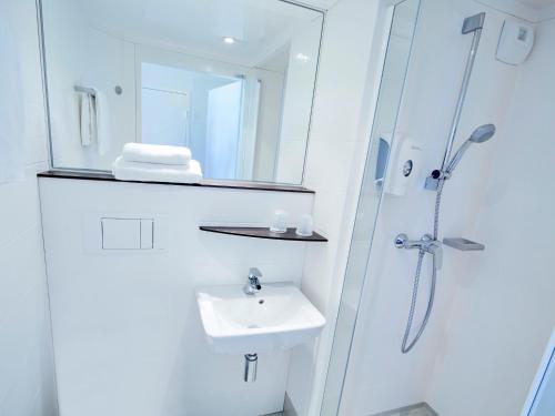 y baño blanco con lavabo y ducha. en Premiere Classe Valence Nord - Saint Marcel Les Valence, en Saint-Marcel-lès-Valence