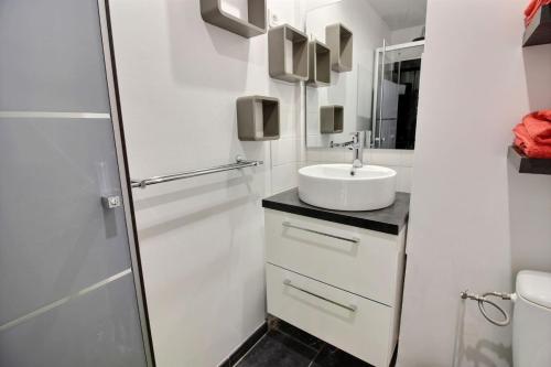 a white bathroom with a sink and a shower at Le port in Perros-Guirec