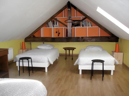 a attic room with two beds and a book shelf at Gîte Bourgeois in Isches