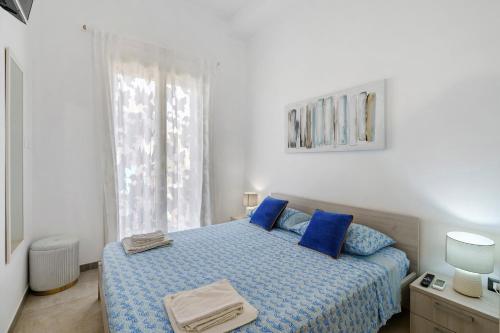 a bedroom with a bed with blue pillows and a window at Maison Vivian Rooms in Marzamemi